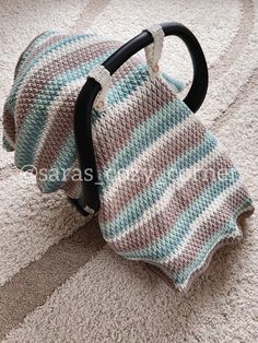 a crocheted baby car seat cover sitting on top of a carpeted floor