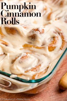 a glass dish filled with cinnamon rolls on top of a wooden table