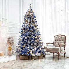 a blue and white christmas tree in a living room next to a chair with gold trim