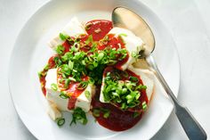 a white plate topped with tofu covered in sauce and garnished with green onions