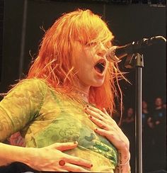 a woman singing into a microphone on stage