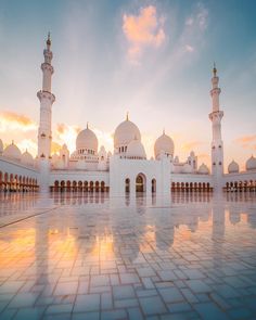 a large white building with many towers and domes on it's sides at sunset