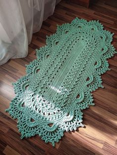 a green crocheted doily laying on the floor next to a white bed