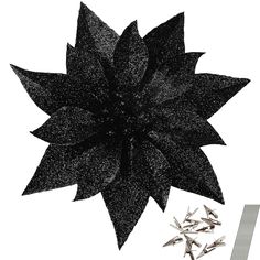 a large black flower sitting on top of a white table next to pins and needles