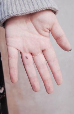 a person's left hand with a tiny ring on it and the word love written in