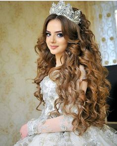 a woman with long curly hair wearing a tiara and holding her hand on her hip