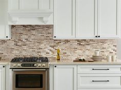 a stove top oven sitting inside of a kitchen next to white cabinets and counter tops