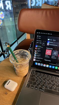 an open laptop computer sitting on top of a wooden table next to a cup of coffee