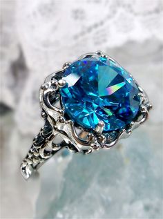 Simulated Aquamarine CZ Ring  Speechless Design#103 Custom Inspired by Victorian era filigree designs, I now offer this stunning Antique inspired ring in sterling silver. This fabulous ring is set with a 6ct flawless Man-made/Simulated Aquamarine gemstone. The round full cut high-quality blue gemstone is 12mm (just shy of 1/2th of an inch) in diameter. The inside of the band is marked 925 for sterling. Notice the beautiful intricate bow and floral-like design of the silver filigree setting and b Victorian Style Rings, Victorian Filigree, Victorian Ring, Antique Filigree, Victorian Rings, Filigree Design, Filigree Ring, Cz Ring, Aquamarine Blue