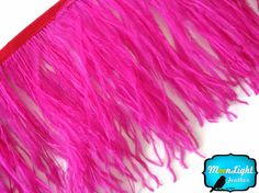 pink ostrich feathers on white background with red trim around the edges and bottom