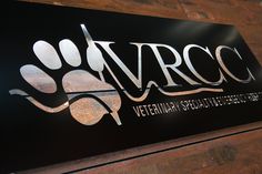 a black and silver sign with the words vrcc written in white lettering on it