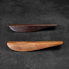 two wooden spoons sitting next to each other on a black surface with dark background