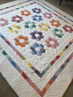 a multicolored quilt is displayed on the floor