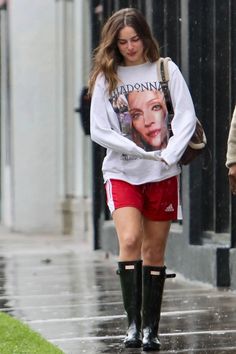 a woman walking down the street wearing rain boots