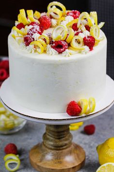 a white cake topped with raspberries and lemon slices