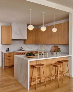 a kitchen with marble counter tops and wooden stools next to an island in the middle