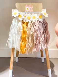 a small wooden stool with flowers on the top and fringes around it's legs