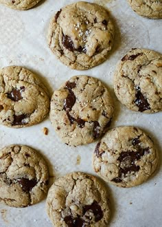 chocolate chip cookies are lined up on a sheet of parchment paper and ready to be eaten