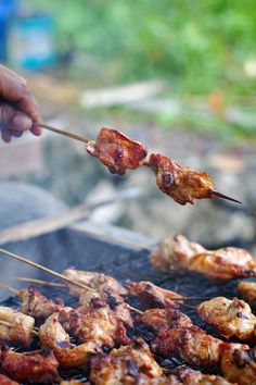 someone is grilling chicken on the grill with skewers in front of them