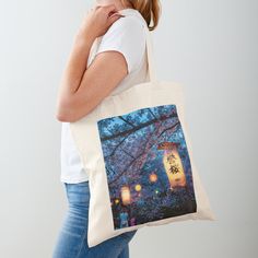 a woman carrying a tote bag with an image of a lantern in the trees