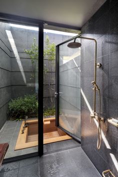 a bathroom with a walk in shower next to a wooden bench and potted plant