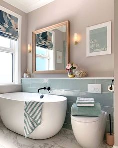 a white bath tub sitting next to a toilet in a bathroom under a mirror above it