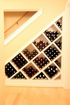 a wine rack with several bottles in it on the floor next to a wall mounted shelf