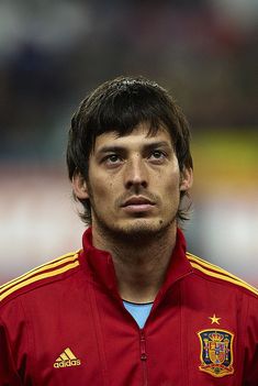 a close up of a soccer player wearing a red jacket