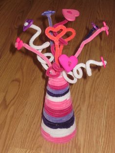 a vase filled with pink and purple items on top of a wooden floor next to a sign that says love