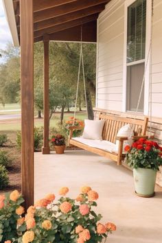 a porch swing with flowers and potted plants on the front porch next to it