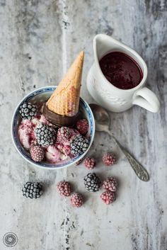 raspberries and ice cream in a bowl next to a cup of chocolate sauce