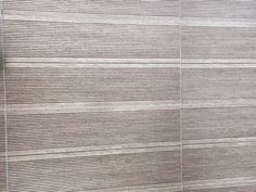 a white toilet sitting next to a wall covered in wooden slatted coverings