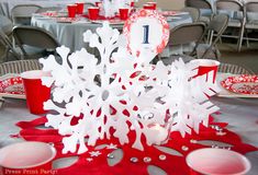 the table is set with red and white plates, silverware, and snowflakes