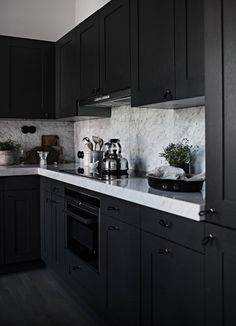 a kitchen with black cabinets and white marble counter tops is seen in this image from the front view