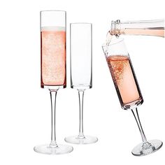 two champagne flutes filled with pink liquid being poured into one glass and the other is empty