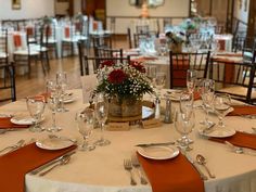 the table is set with silverware and orange napkins