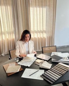 a woman sitting at a table surrounded by papers