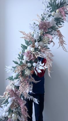 a man is standing next to a christmas tree with pink and white decorations on it