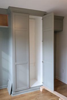 an empty room with white cupboards and wood floors