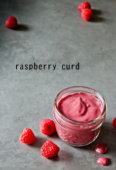 raspberry curd in a glass jar surrounded by raspberries