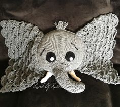 an elephant stuffed animal with crocheted wings and eyes is on a black blanket