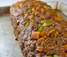 a piece of meat sitting on top of a pan covered in sauce and seasoning