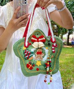 a woman taking a photo with her cell phone while wearing a crocheted purse