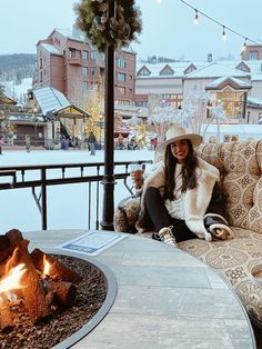 a woman sitting on top of a couch next to a fire pit