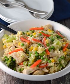 a white bowl filled with chicken and veggies on top of a wooden table