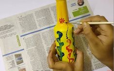 a person holding a pencil and drawing on a yellow bottle