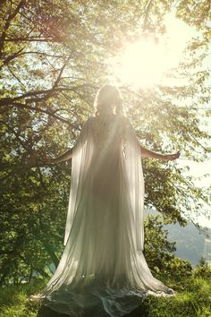 a woman in white dress standing on top of a lush green field