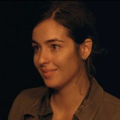 a close up of a person wearing a brown shirt and earring on their ears