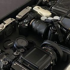 a bunch of cameras sitting on top of a black table next to another set of camera's