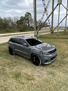 a grey jeep is parked in the grass near a metal structure on a cloudy day